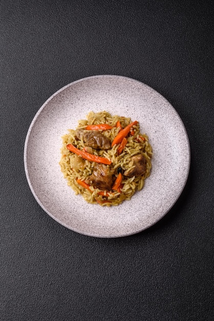 Délicieux pilaf avec des légumes, du sel, des épices et des herbes dans une assiette en céramique