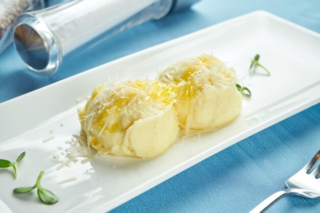 Délicieux plat d'accompagnement pour les plats principaux - purée de pommes de terre au parmesan à la crème dans une assiette blanche sur une nappe bleue