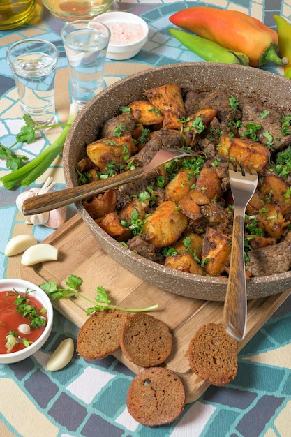 Délicieux plat géorgien ojaxuri avec du boeuf frit et des pommes de terre au four décorant avec de l'aneth et de l'oignon à la coriandre verte fraîche