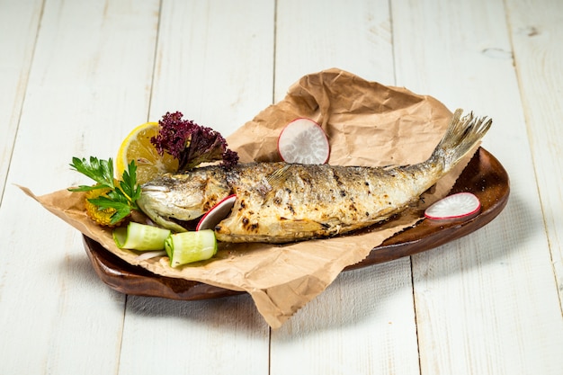 Photo délicieux poisson grillé aux légumes sur fond de bois blanc