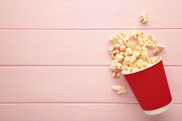 Délicieux pop-corn sur fond en bois rose clair. Espace pour le texte