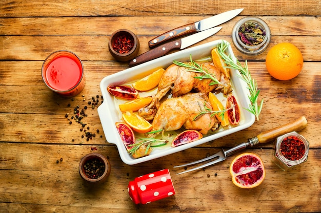 Délicieux poulet cuit au four avec des oranges et du romarin dans un plat allant au four. Pilon de poulet cuit au four