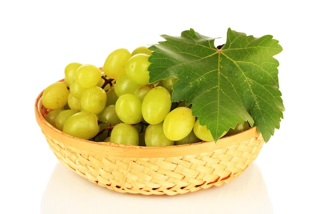 Délicieux raisins mûrs dans un panier en osier isolés sur blanc