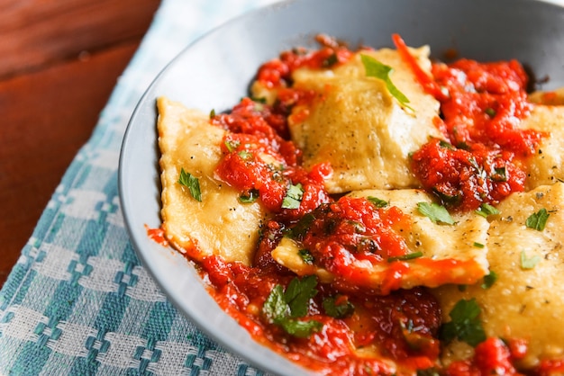 Délicieux raviolis à la sauce tomate dans une assiette sur fond de bois