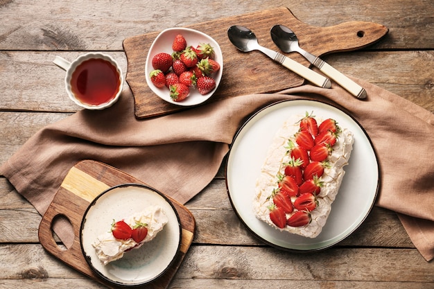 Délicieux rouleau de meringue aux fraises et thé sur table