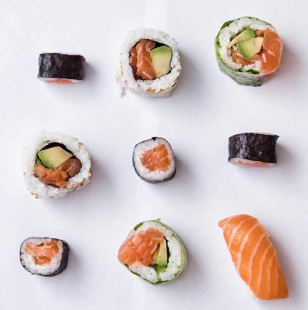 Un délicieux rouleau de sushi avec des baguettes en bois sur un fond blanc