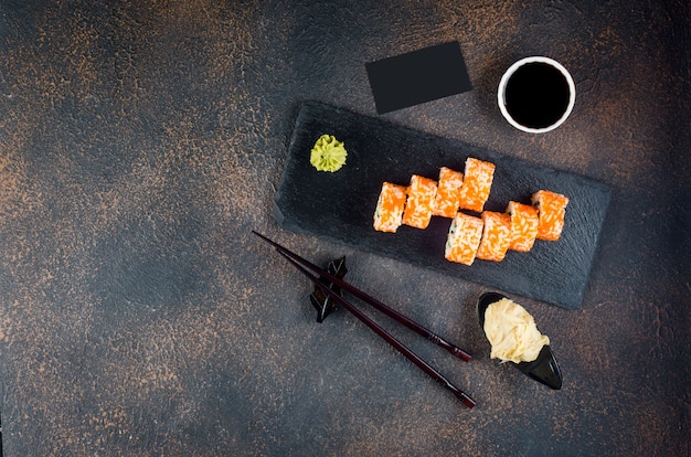 Délicieux rouleaux californiens et Maki sur plaque de pierre avec sauces, baguettes, gingembre et wasabi