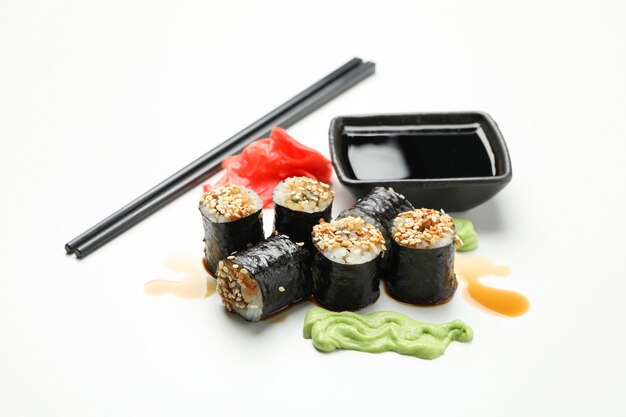 Délicieux rouleaux de sushi, sauces et baguettes sur une surface blanche