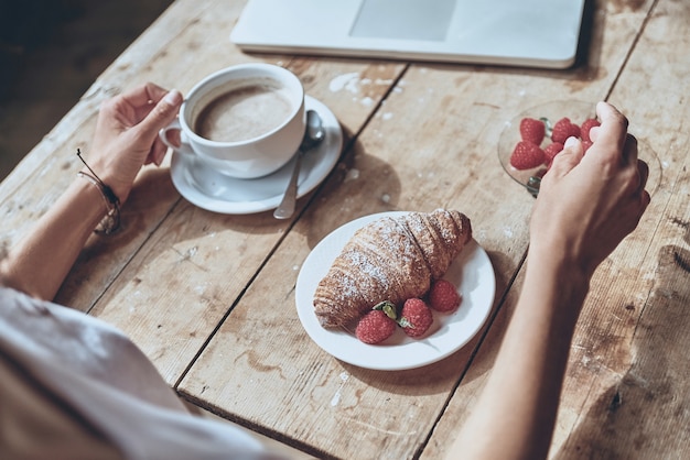 délicieux et sain. gros plan de femme prenant son petit déjeuner avec croissant, fraise