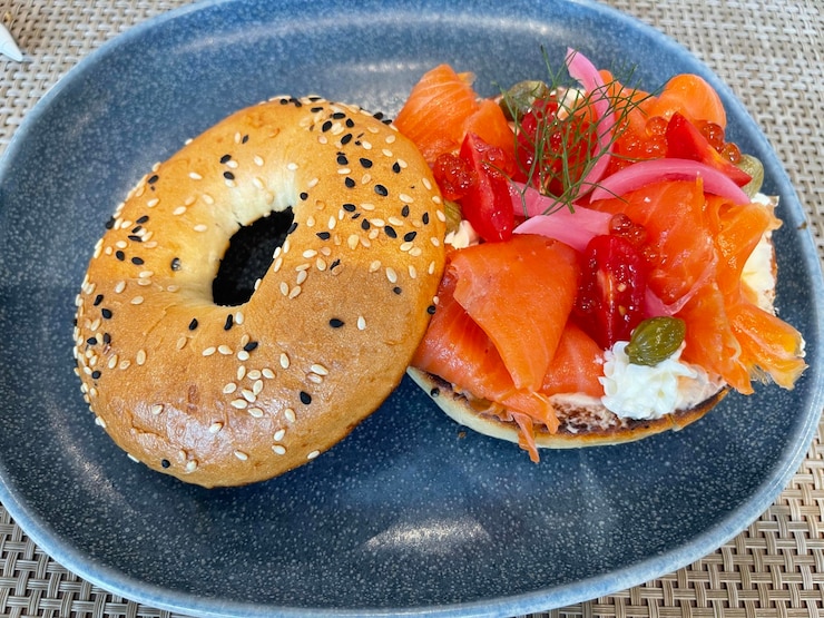 Photo délicieux sandwich au bagel avec saumon fumé, épinards, oignons rouges, tomates, avocats et fromage à la crème.