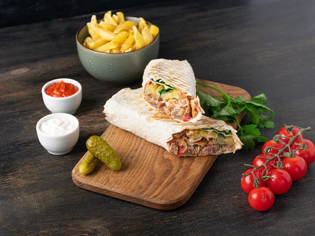 Photo délicieux sandwich shawarma sur fond de bois avec frites et cornichons