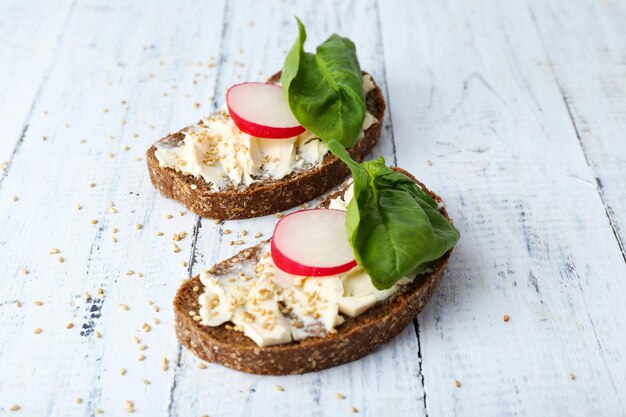 Photo délicieux sandwichs au radis et basilic sur fond de bois