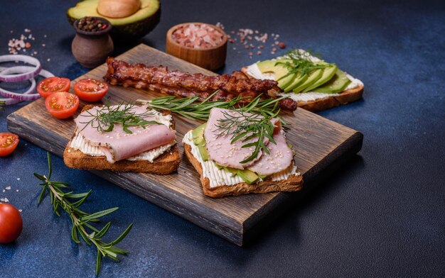 De délicieux sandwichs frais au beurre de jambon, à l'avocat et aux graines de sésame sur une planche à découper en bois