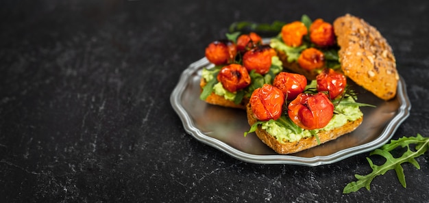 Délicieux sandwichs végétaliens avec purée d'avocat, tomates rôties et roquette