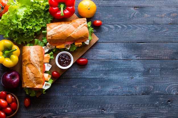 Délicieux et savoureux sandwiches à la dinde, jambon, fromage, tomates sur fond en bois