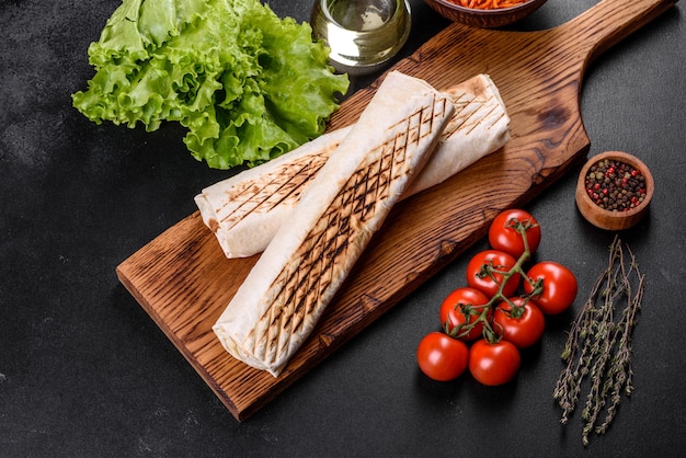 Délicieux shawarma frais avec de la viande et des légumes sur une table en béton foncé. Restauration rapide, cuisine turque