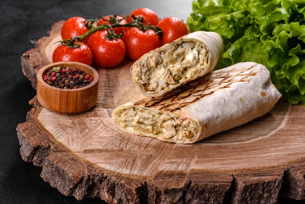 Délicieux shawarma frais avec de la viande et des légumes sur une table en béton foncé