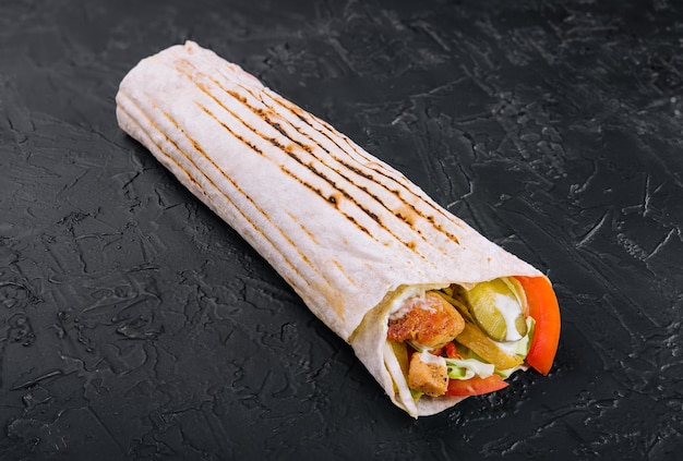 Délicieux shawarma sur une planche de bois sur une table en bois sombre