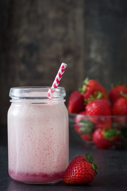 Délicieux smoothie aux fraises en pot sur table en bois