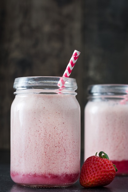 Délicieux smoothie aux fraises en pot sur table en bois