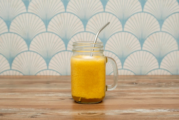 Délicieux smoothie aux fruits de la passion en verre avec paille en métal sur table en bois