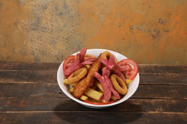 Délicieux snack assiette frites rondelles d'oignon rouleaux de printemps ou saucisses sur la table