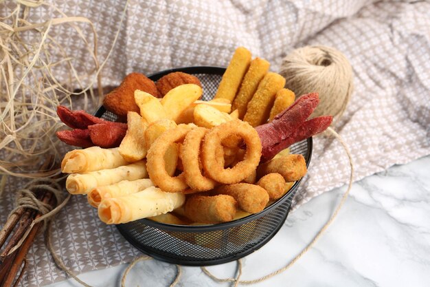 Délicieux snack assiette frites rondelles d'oignon rouleaux de printemps ou saucisses sur la table