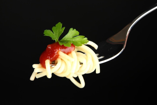 Photo de délicieux spaghettis sur la fourchette gros plan sur fond noir