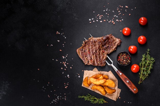 Délicieux steak de boeuf frais juteux avec des épices et des herbes sur un fond de béton foncé. Plats grillés