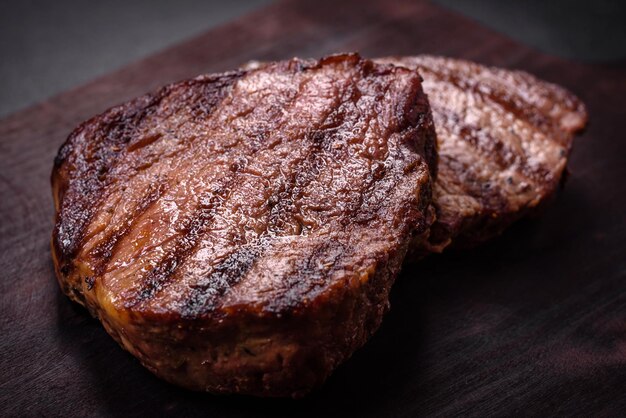 Délicieux steak de boeuf juteux frais avec des épices et des herbes sur un fond de béton foncé