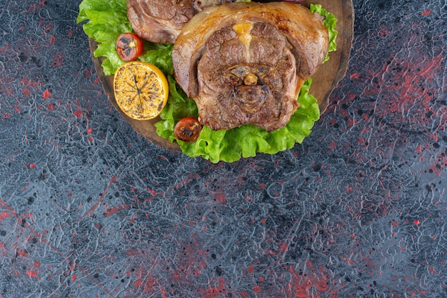 Délicieux steak juteux frais avec salade de laitue placé sur une planche à découper en bois.