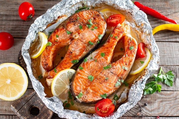 Délicieux steak de saumon frais cuit avec des épices et des herbes cuites sur un gril sur une table en bois. Nourriture saine de fruits de mer. Vue de dessus