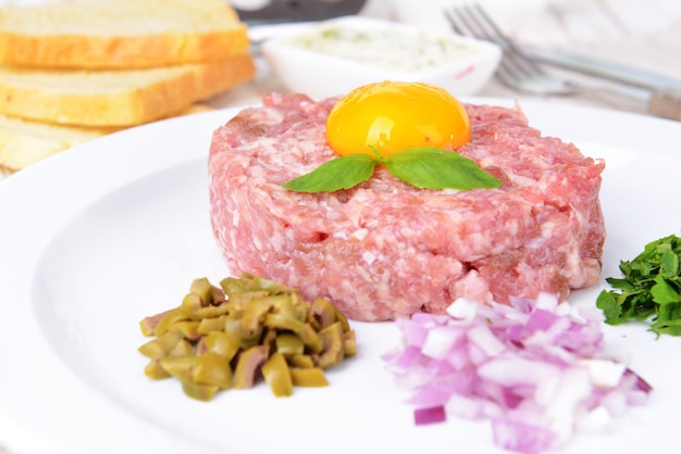 Délicieux steak tartare avec du jaune sur la plaque sur le gros plan de table