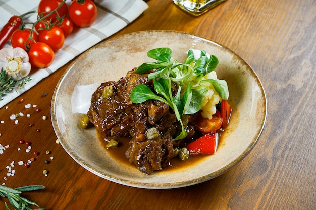 Délicieux steak de veau italien Ossobuco alla ragoût milanais avec gremolata et légumes sur table en bois. Gros plan, mise au point sélective. Nourriture savoureuse au restaurant.