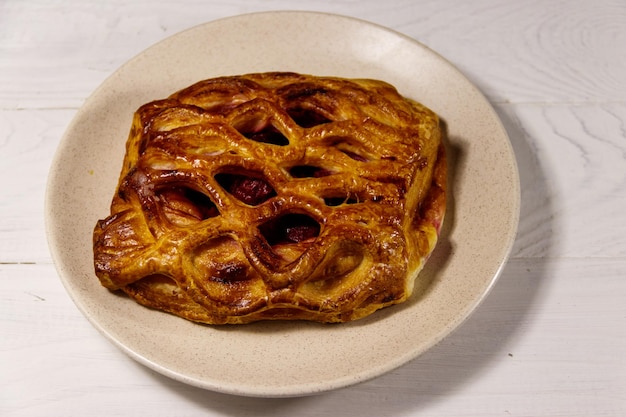 Délicieux strudel aux cerises sur table en bois blanc