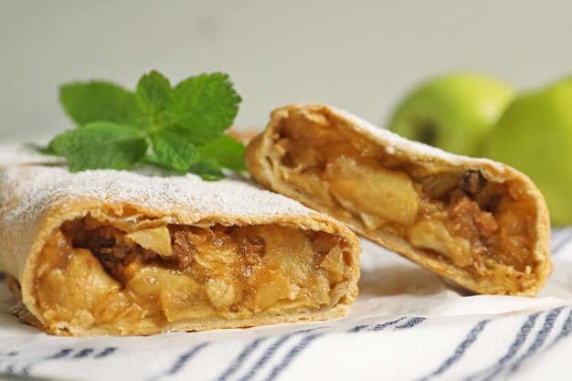 Un délicieux strudel avec des pommes, des noix et du sucre en poudre sur la table.