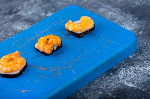 De délicieux sushis frais aux crevettes placés sur une planche à découper en bois.