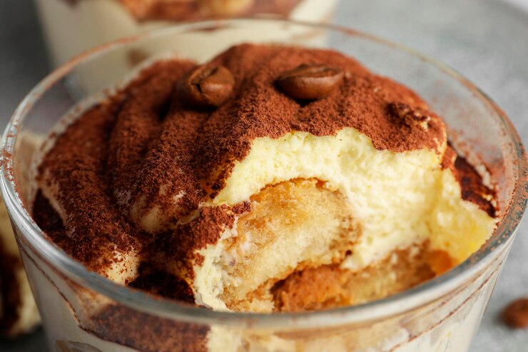 Photo un délicieux tiramisu en verre et des grains de café en gros plan sur la table