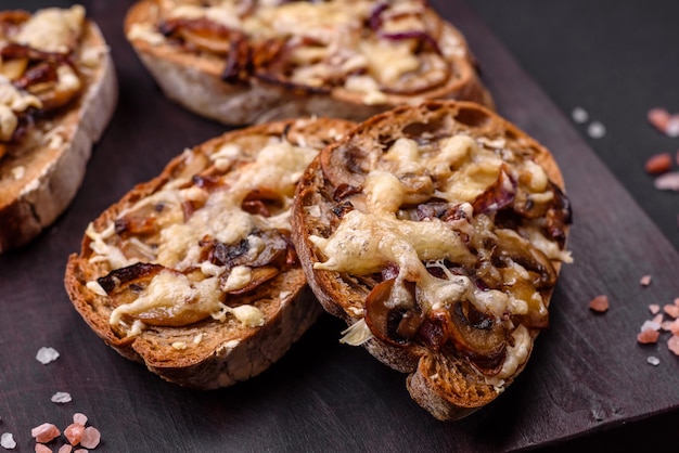 Délicieux toast croustillant ou bruschetta aux champignons champignons oignons frits et fromage aux épices et herbes sur fond de béton foncé