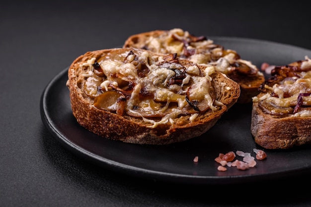 Délicieux toast croustillant ou bruschetta aux champignons champignons oignons frits et fromage aux épices et herbes sur fond de béton foncé