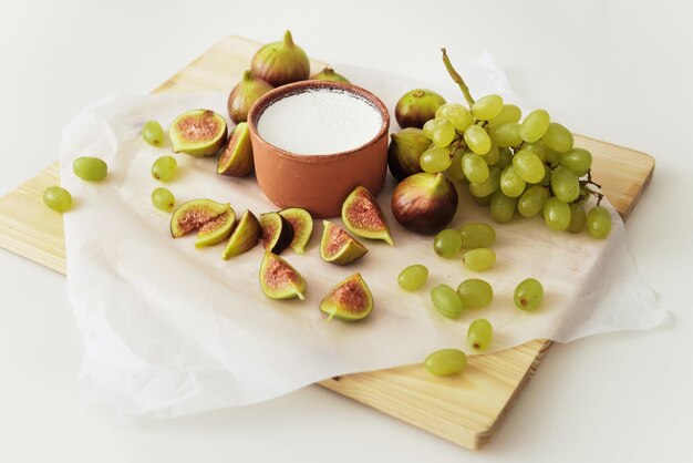 Délicieux yaourt grec naturel dans un bol d'argile avec des figues et du raisin