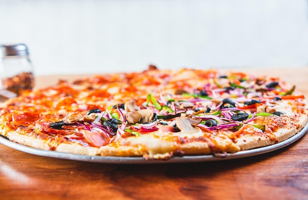 Delicious Supreme Pizza et pepperoni sur du bois avec un espace de copie Vue rapprochée de la pizza suprême avec des olives sur une table en bois