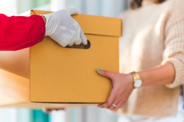 Delivery man donnant des boîtes aux jeunes femmes à la maison, concept de service de messagerie