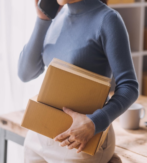 Démarrage PME petite entreprise entrepreneur de femme asiatique indépendante à l'aide d'un ordinateur portable avec boîte Succès joyeux femme asiatique sa main lève la boîte d'emballage de marketing en ligne et livraison concept d'idée PME