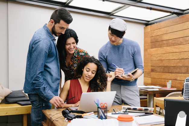 Démarrage de quatre personnes multiethniques discutant joyeusement d'idées dans un espace de coworking moderne
