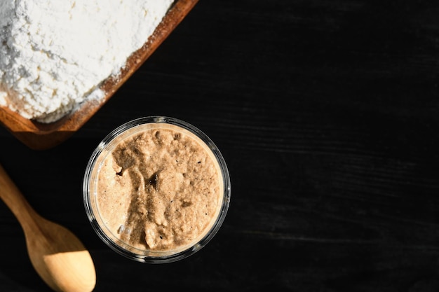 Démarreur de levain de seigle et de blé actif dans un bocal en verre avec de la farine d'ingrédients Vue de dessus