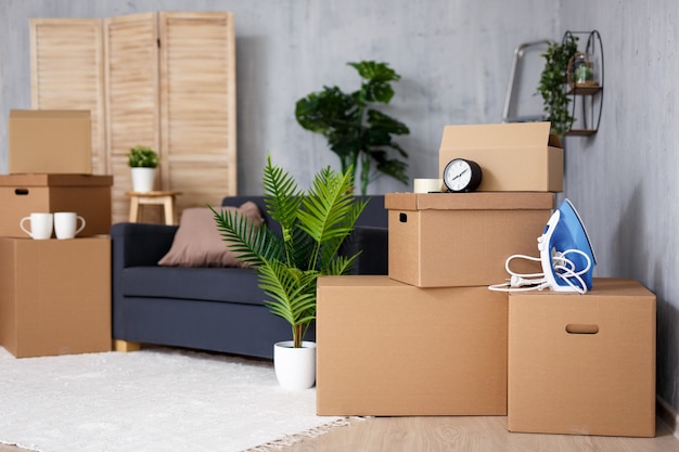 Déménagement dans une nouvelle maison - pile de boîtes en carton marron avec des effets personnels dans le salon après le jour du déménagement