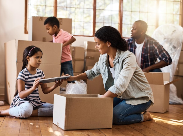 Photo déménagement de la famille et des cartons d'emballage dans le salon de la maison avec les enfants maman et papa investissement immobilier et déménagement avec quelques enfants aidant le déballage des cartons et des cartons