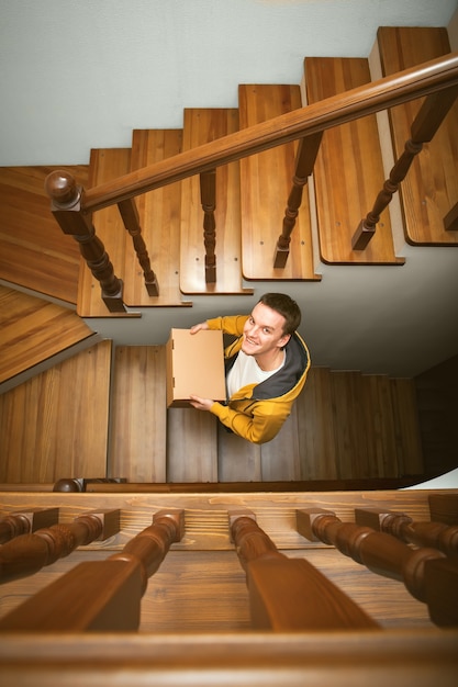 Déménagement. Jeune homme avec des boîtes en carton dans un escalier.