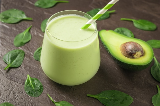 Un demi-avocat et un verre de smoothies sur fond de pierre avec des feuilles d'épinards. Produit de remise en forme. Nutrition sportive diététique.